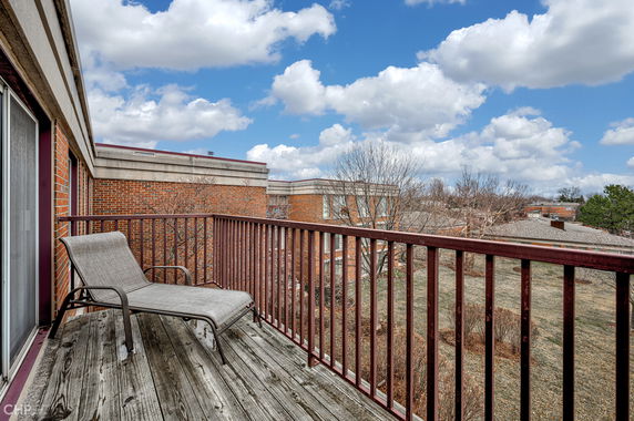 Panoramic view from a balcony showing surrounding buildings and a grassy area.