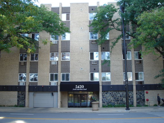 Front view of a multi-story apartment building with brick facade and main entrance.