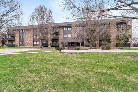 Front view of a three-story brick apartment building with multiple balconies.