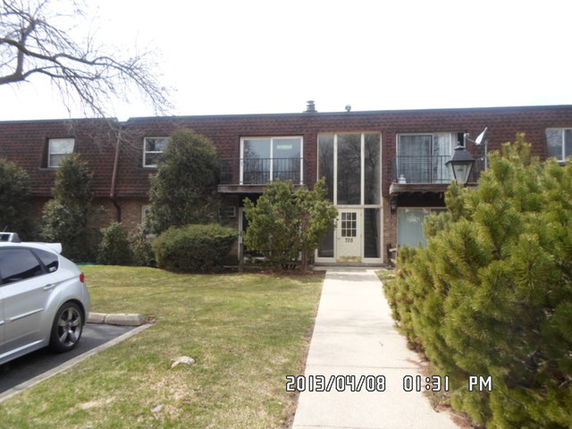 Front view of a two-story building with balconies and glass entrance door.