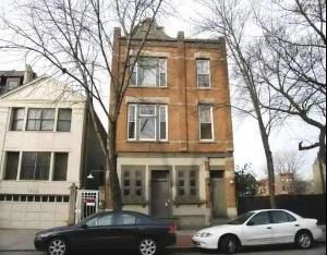 Front view of a three-story brick building with large windows.