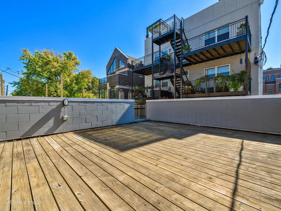 Rooftop view with wooden deck and nearby residential buildings.