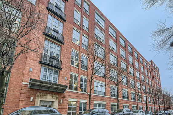 Front view of a multi-story brick building with large windows.