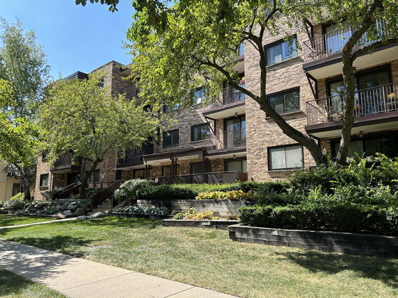 Front view of a multi-story apartment building with balconies and brick facade.