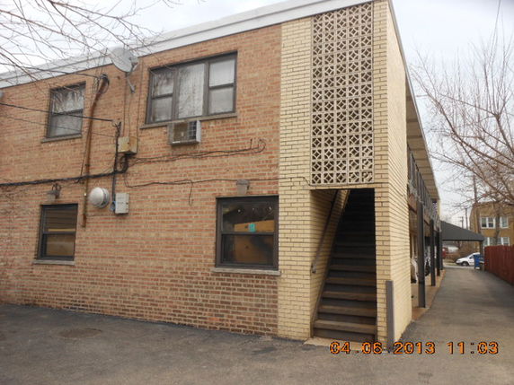 Front view of a two-story brick building with exterior stairs.
