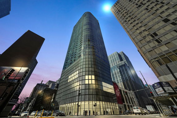 Front view of a tall glass skyscraper in a cityscape.
