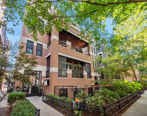 Front view of a multi-story brick building with balconies and large windows.