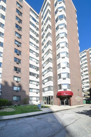 Front view of a multi-story brick apartment building with large windows.