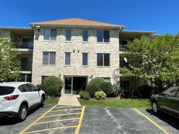 Front view of a three-story apartment building with a parking area.