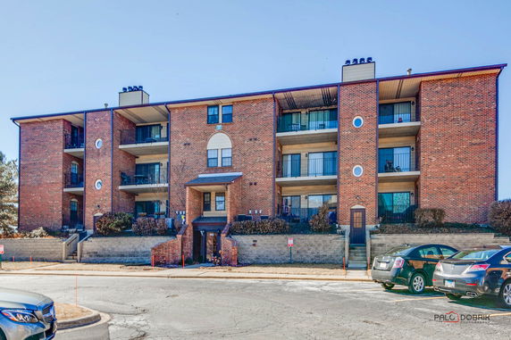 Front view of a multi-story brick apartment building with balconies.
