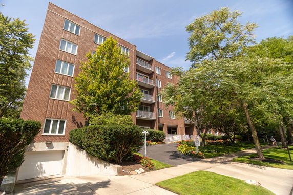 Front view of a multi-story brick building with balconies and a walkway.