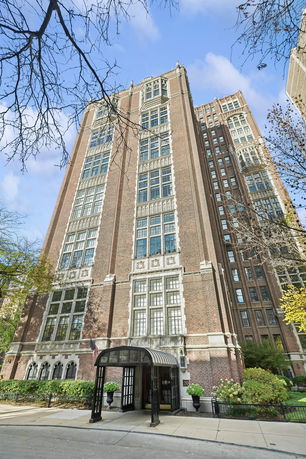 Front view of a tall, multi-story brick building with large windows.