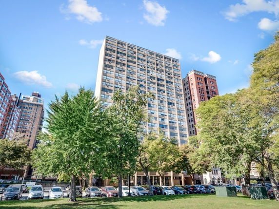 Front view of a tall residential building with multiple floors and balconies.