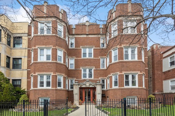 Front view of a multi-story brick building with multiple windows and an ornate entrance.