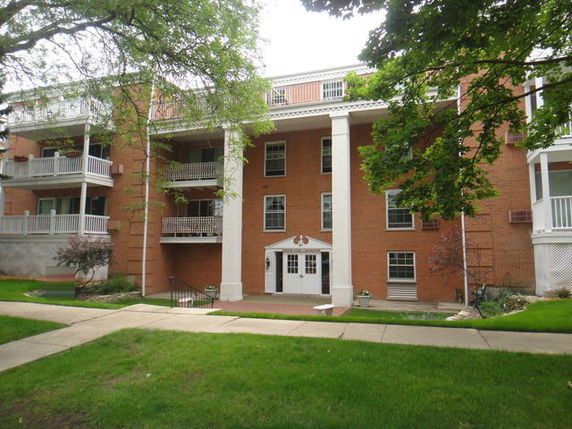 Front view of a three-story brick building with white columns and balconies.
