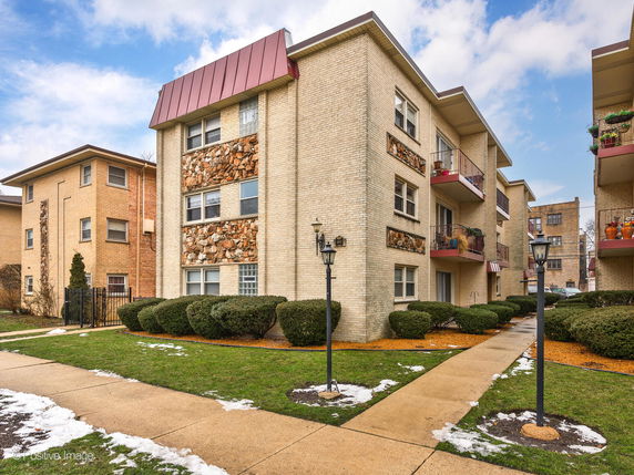 Front view of a multi-story apartment building with brick exterior and balconies.