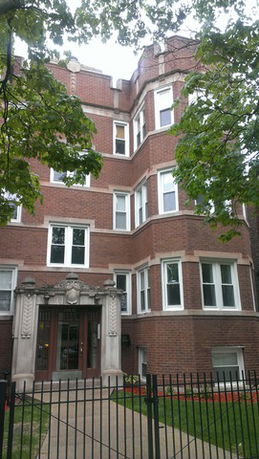 Front view of a multi-story brick building with a decorative entrance.