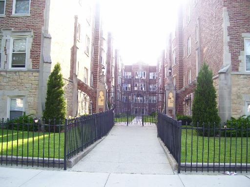 Front view of a multi-story apartment building with a pathway and ornate entrance.