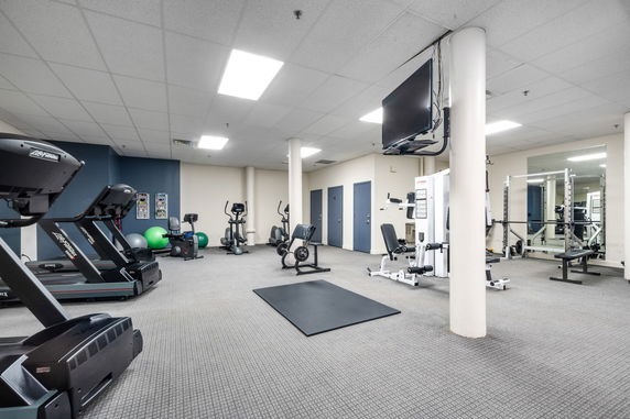 Interior view of a fitness room with exercise equipment and machines.