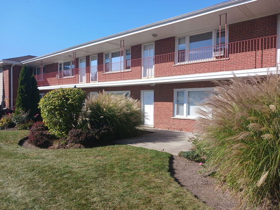 Front view of a two-story brick building with balconies and multiple entrances.