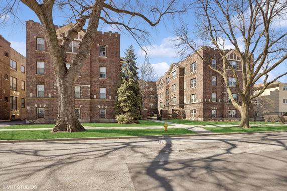 Front view of a brick apartment building with multiple floors and detailed architecture.