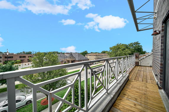 View from a balcony with a metal railing overlooking surrounding buildings and trees.