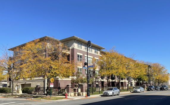 Front view of a multi-story brick building with trees lining the street.
