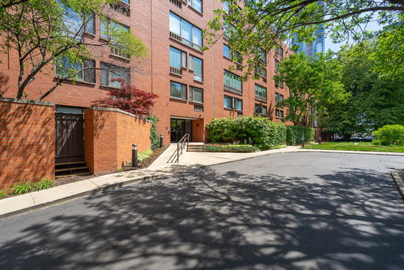 Front view of a multi-story brick apartment building with windows and a walkway.
