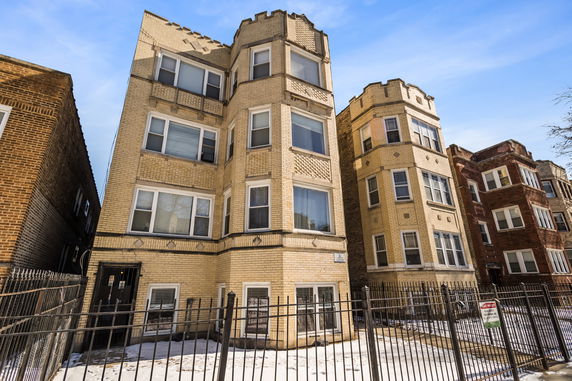 Front view of a multi-story brick apartment building with distinctive corner design.