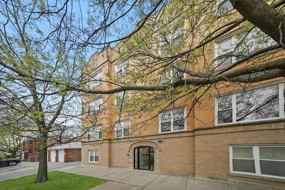 Front view of a multi-story brick building with arched entryway and multiple windows.