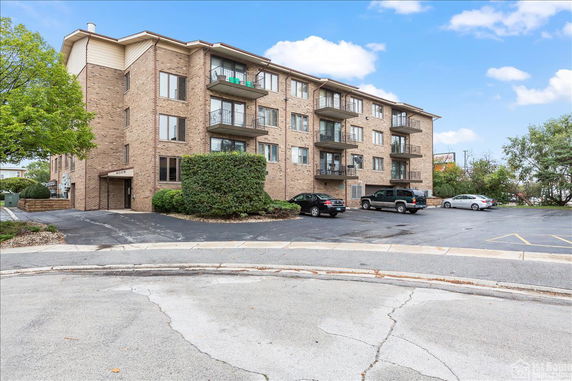 Front view of a multi-story brick apartment building with balconies.