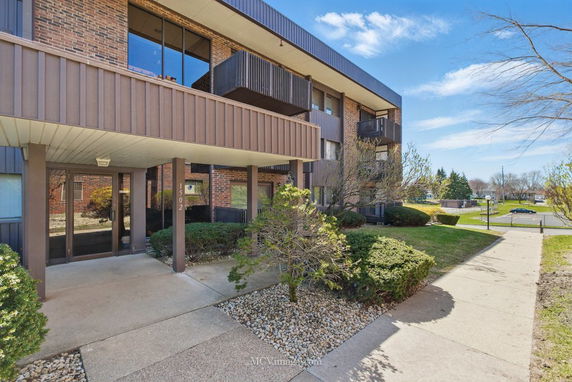 Front view of a multi-story brick building with balconies and entrance.