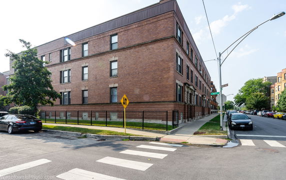 Front view of a multi-story brick building on a street corner.
