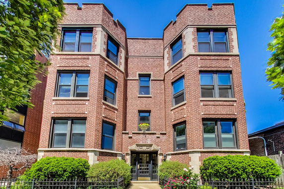 Front view of a multi-story brick building with large windows.