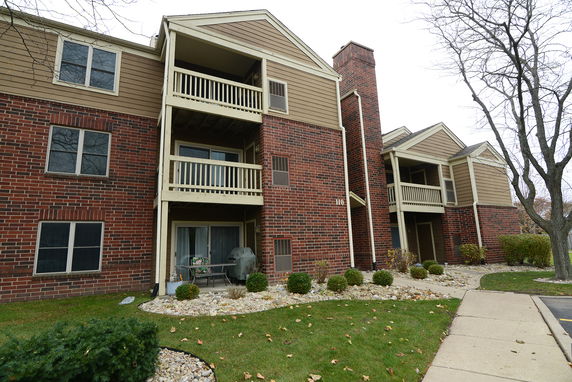Front view of a multi-story apartment building with balconies and brick facade.