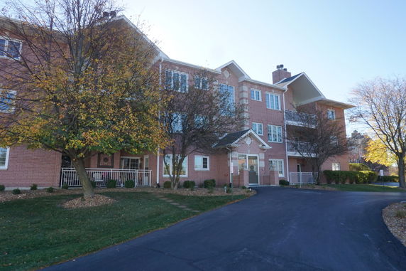 Front view of a multi-story brick building with balconies and a driveway.