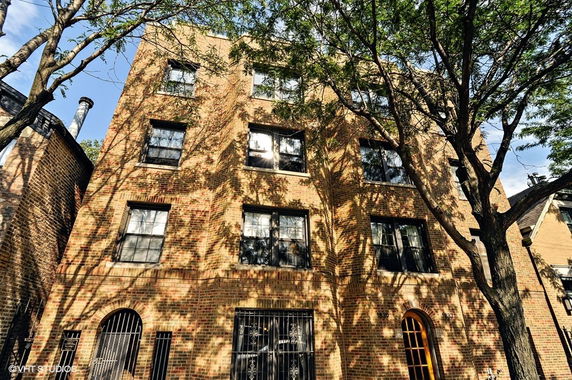 Front view of a multi-story brick building with multiple windows and an entrance at the bottom.