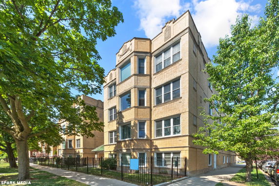 Front view of a four-story brick apartment building with multiple windows and decorative elements.