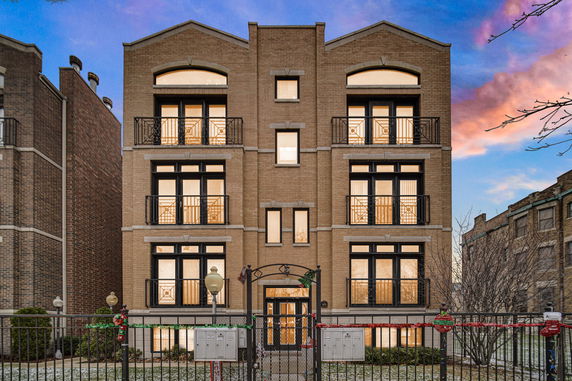 Front view of a multi-story brick building with balconies and black-framed windows.