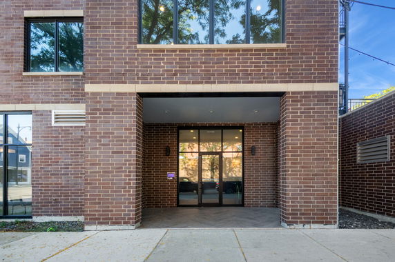Front view of a brick building entrance with large windows.