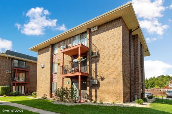 Front view of a multi-story brick apartment building with balconies.