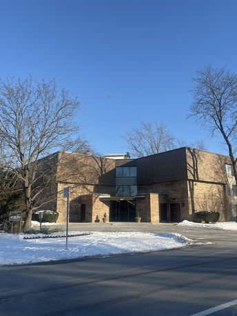 Front view of a two-story brick building with a central entrance under a flat canopy.