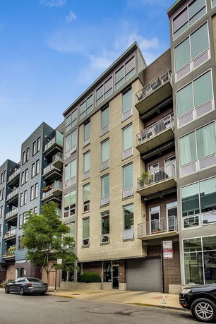 Front view of a multi-story residential building with large windows and balconies.