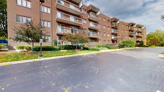 Front view of a multi-story apartment building with balconies and brick exterior.