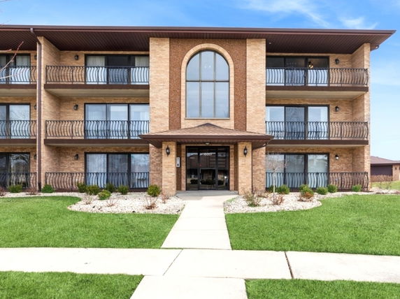 Front view of a multi-story apartment building with balconies.