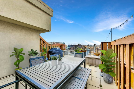 Rooftop with outdoor dining area, potted plants, and city view.