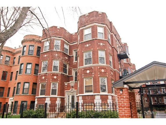 Front view of a multi-story brick building with decorative elements and a covered entryway.