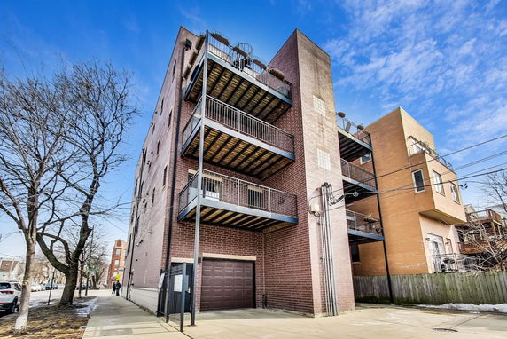 Front view of a multi-story building with multiple balconies and a garage door.