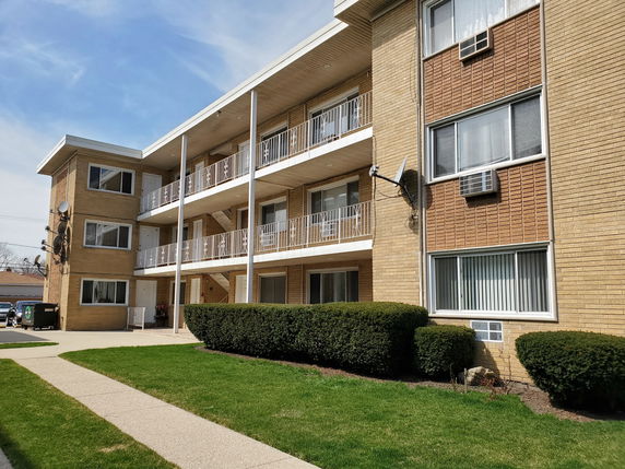 Front view of a three-story apartment building with balconies.