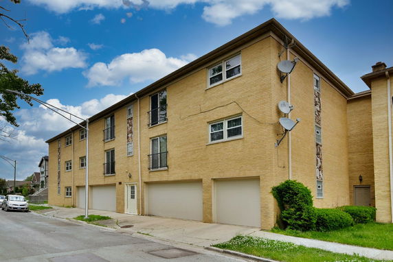 Front view of a three-story brick apartment building with multiple garage doors.